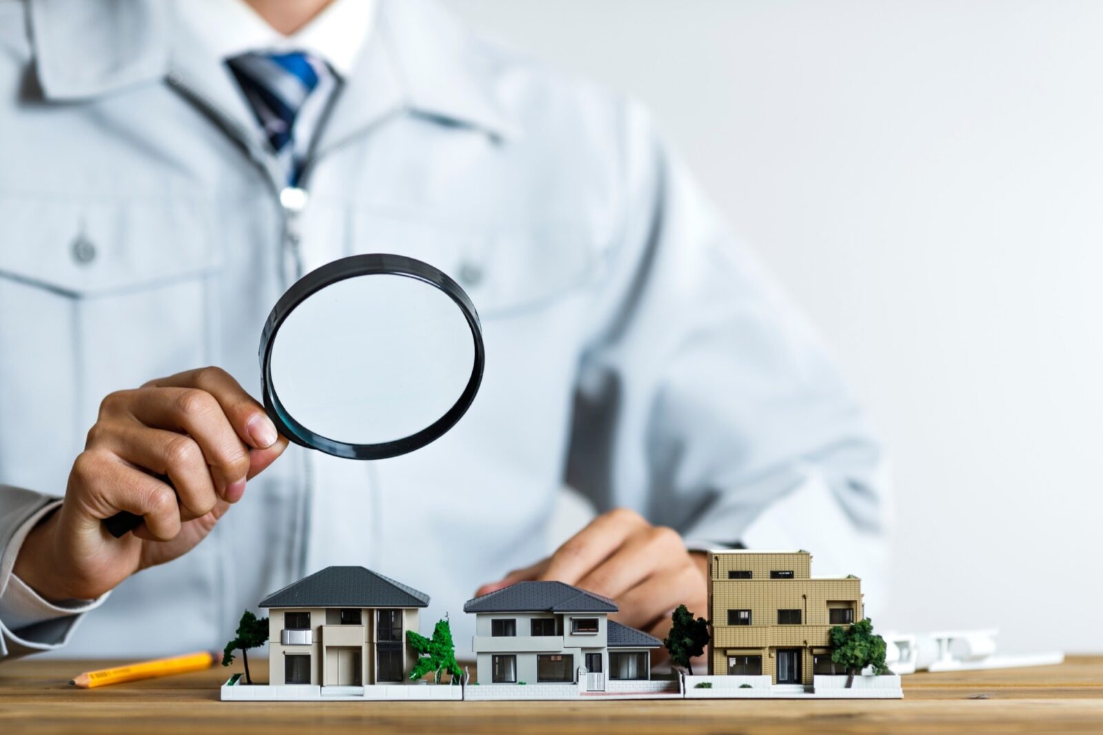 住宅模型をルーペで覗く作業服の男性